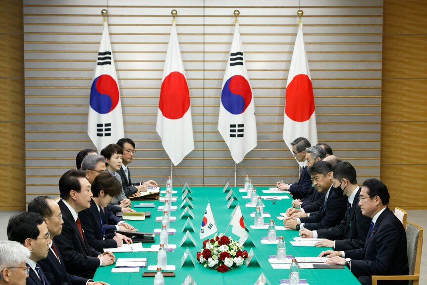 Bilateral meeting between leaders of Japan and South Korea, with their flags in the background.