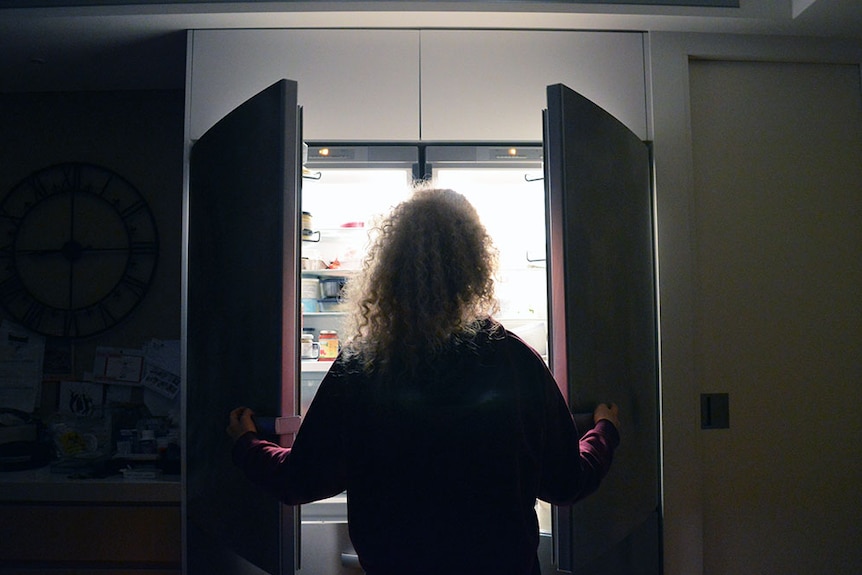 Unidentified woman looking into an open fridge