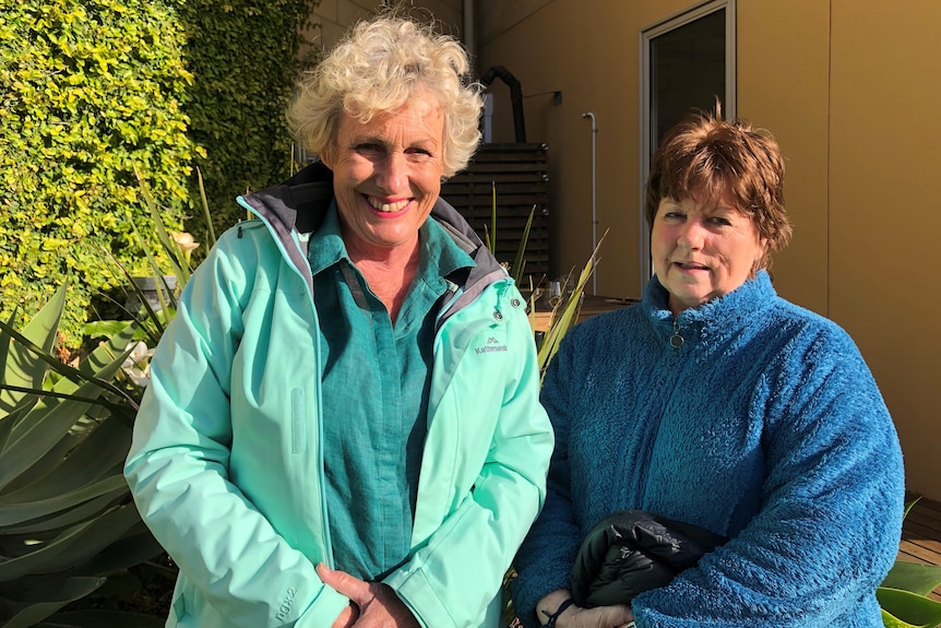 Two women wearing warm jackets stand together.