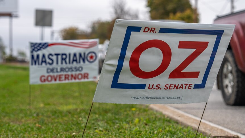 A blue, red and white sign leans to the right reading "Dr Oz US Senate"