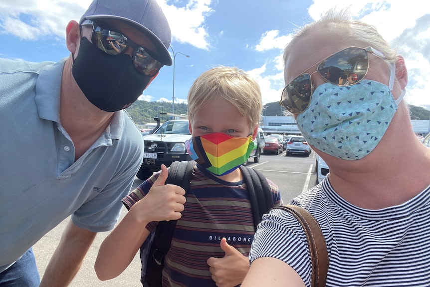 A mother, father and young son take a selfie, all wearing masks.
