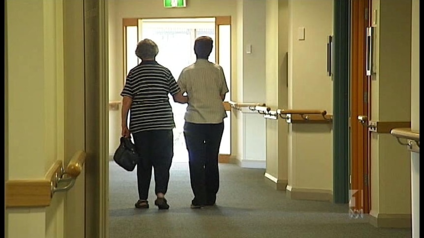 Two people walking toward an exit door in an aged care facility
