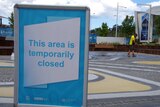 A sign tells visitors to Elizabeth Quay the water park is closed, while a contractor cleans in the background.