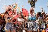 A group of young women with fans laughing as water droplets spray through the air 