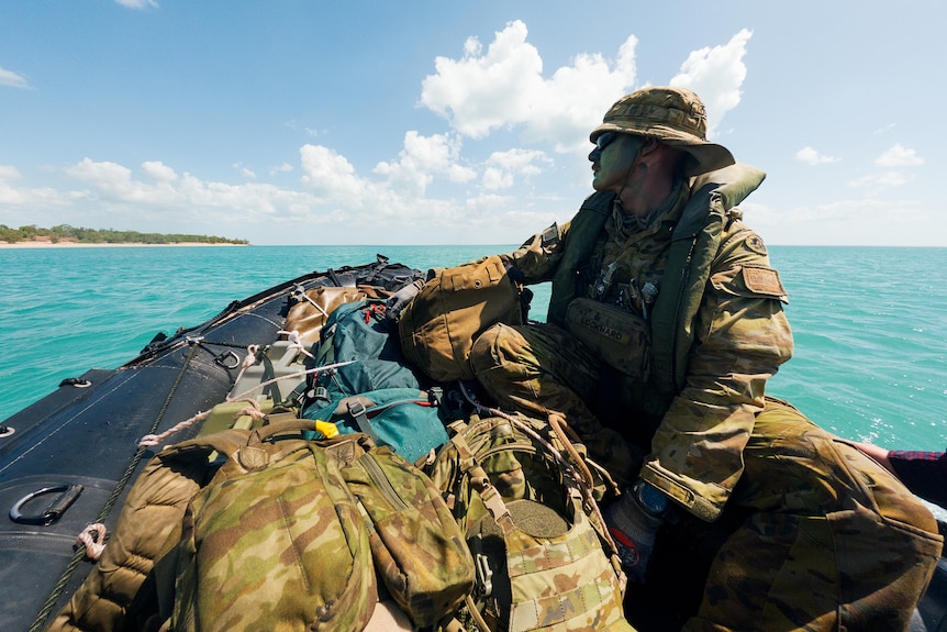 man in army uniform on boat on bright blue ocean