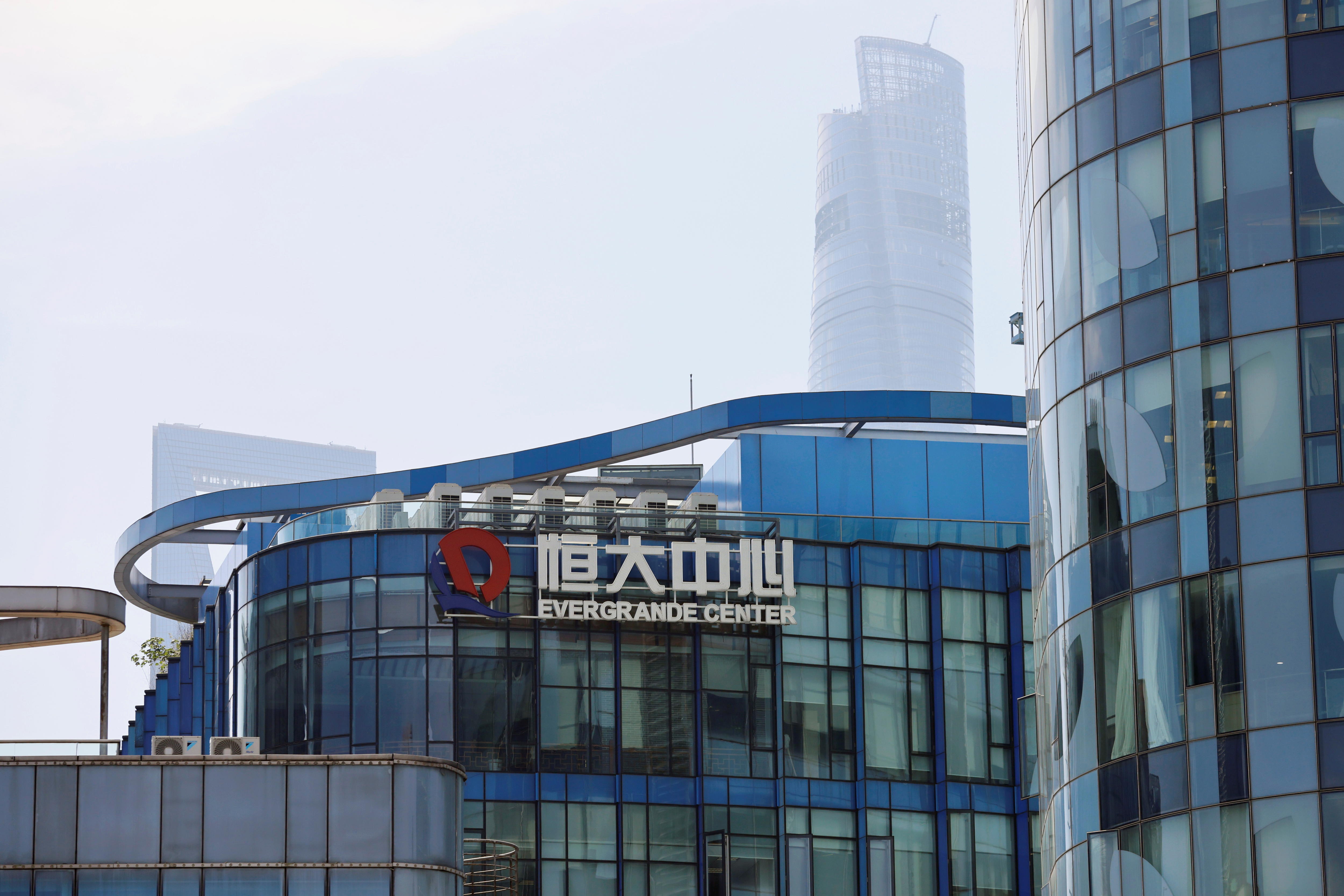 The logo of the China Evergrande Group on the side of a glass office building with fog in the background.