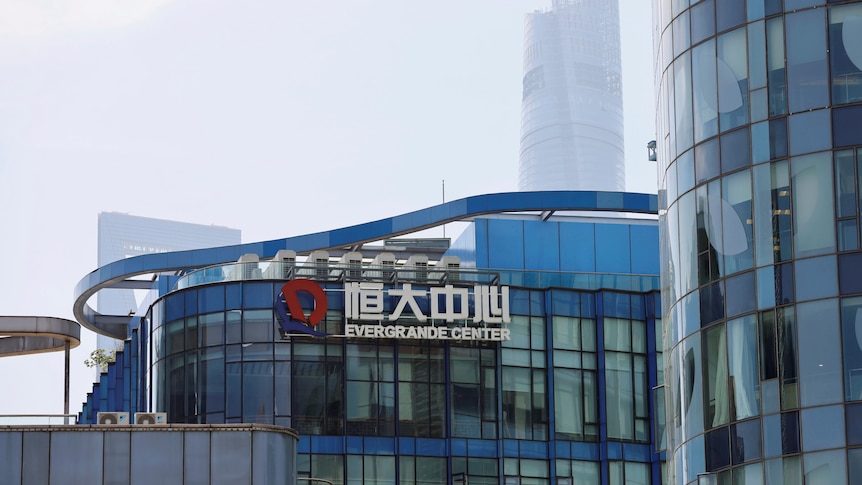 The logo of the China Evergrande Group on the side of a glass office building with fog in the background.