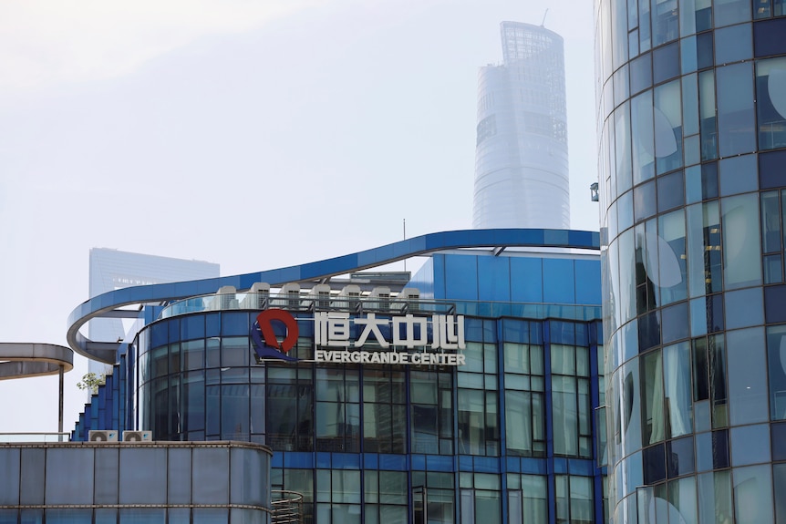 The logo of the China Evergrande Group on the side of a glass office building with fog in the background.