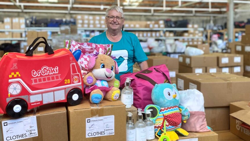 A man standing behind boxes of gifts for children