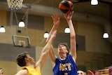 A player jumps to shoot a hoop as another player tries to block him