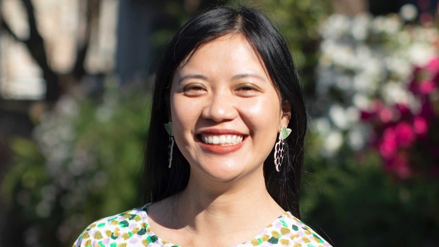 Tina Tran smiles for a photo wearing a colourful top in a story about life 10 years after having cancer.