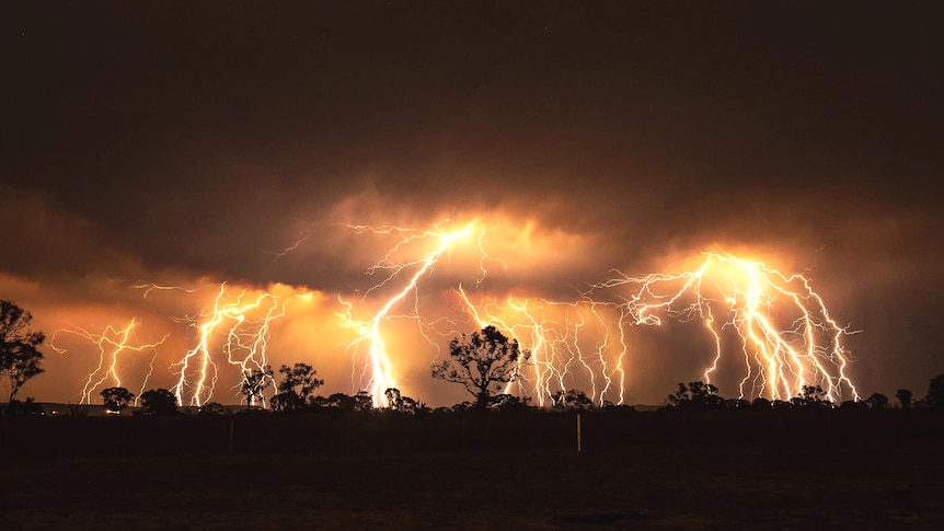 A dry lightning storm at night lights up a rural landscape