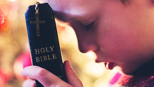Child with bible, generic image for religion, prayer, faith, abuse by clergy.