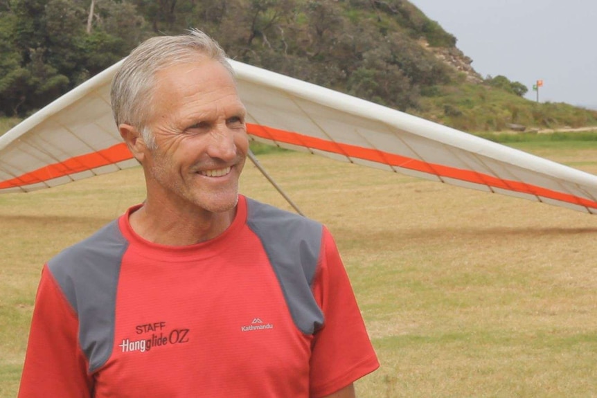 Illawarra hang glider pilot Tony Armstrong talks in front of his hang glider.