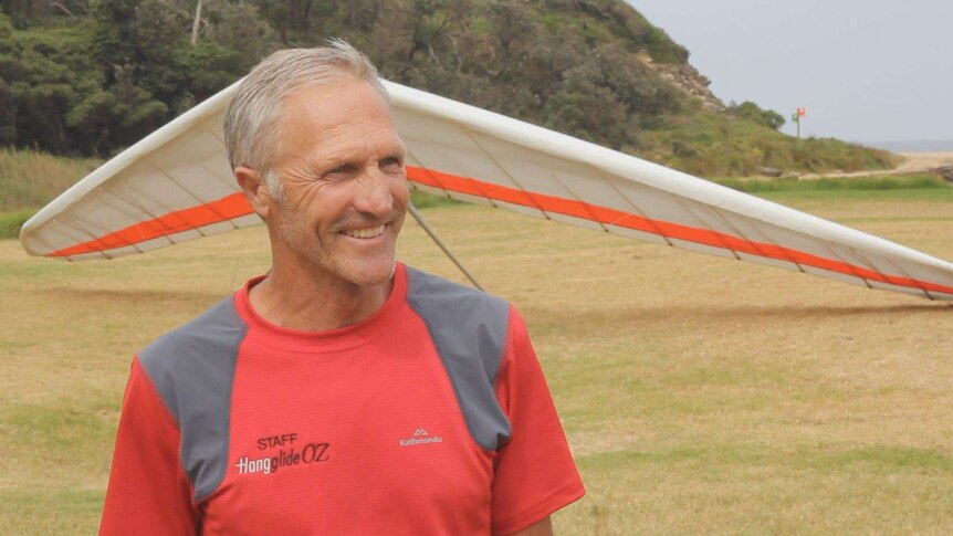 Illawarra hang glider pilot Tony Armstrong talks in front of his hang glider.