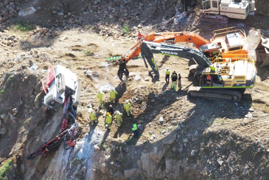 A man trapped in an excavator hanging over the edge of a quarry in Keperra
