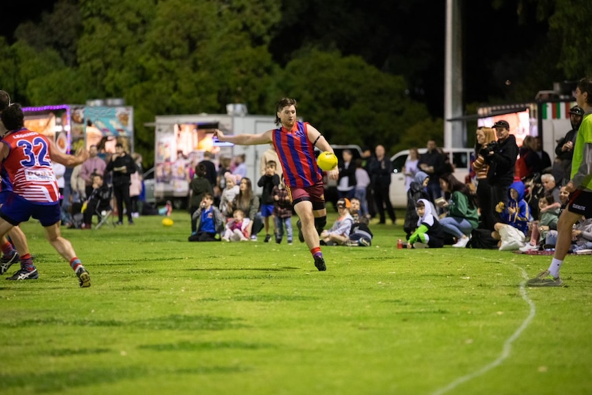 A player on the field preparing to kick a football with spectators in the background 