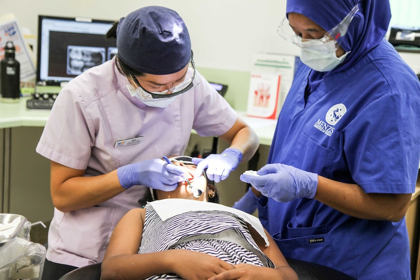 A dentist operates on a child.