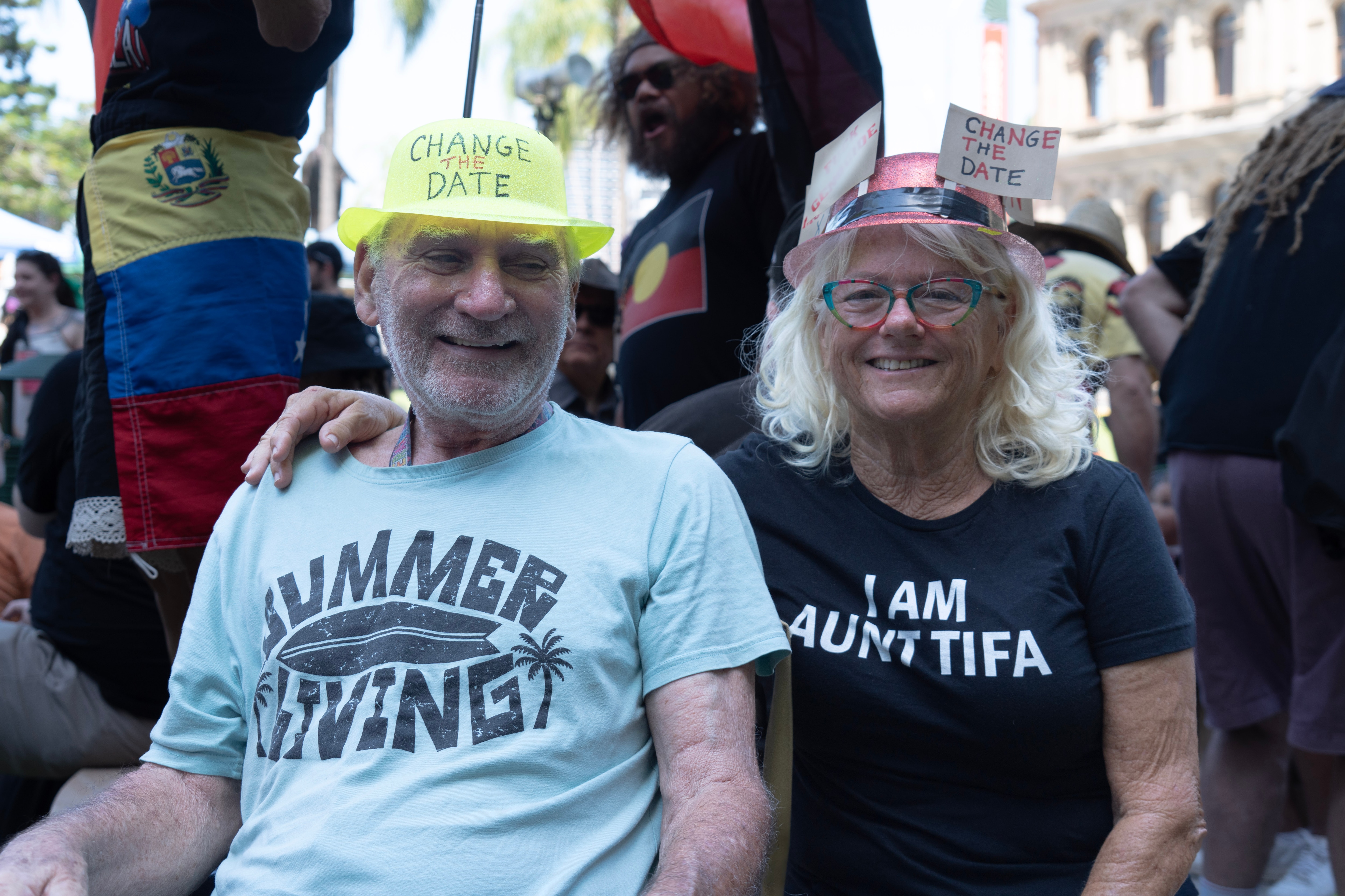 A man and a woman smile wearing hats with the words "change the date".