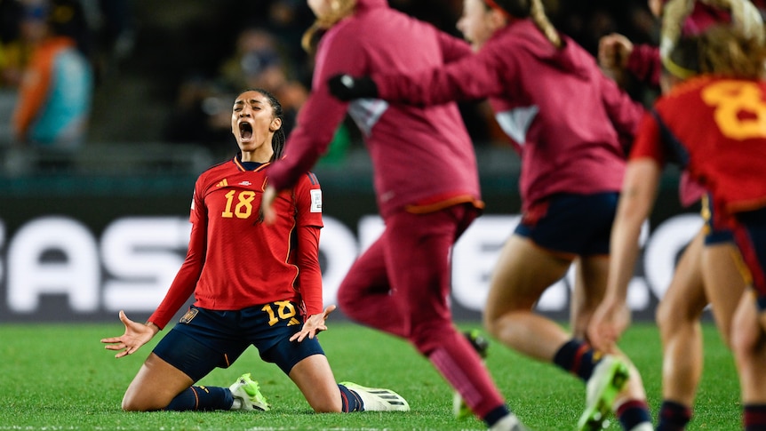 Salma Paralluelo screams on her knees as Spain teammates run onto the field after a Women's World Cup win.