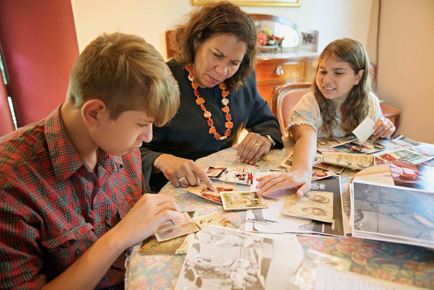 Leanne Liddle looks at old photos with her children Tilly and Jack.