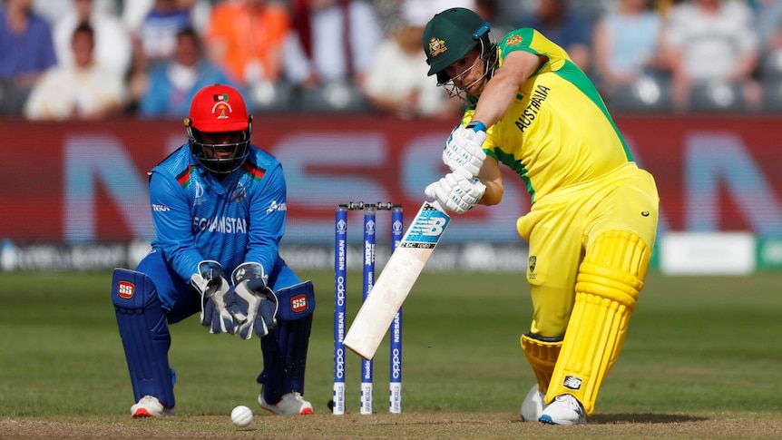 Aaron Finch drives hard through the covers while the wicketkeeper watches on.