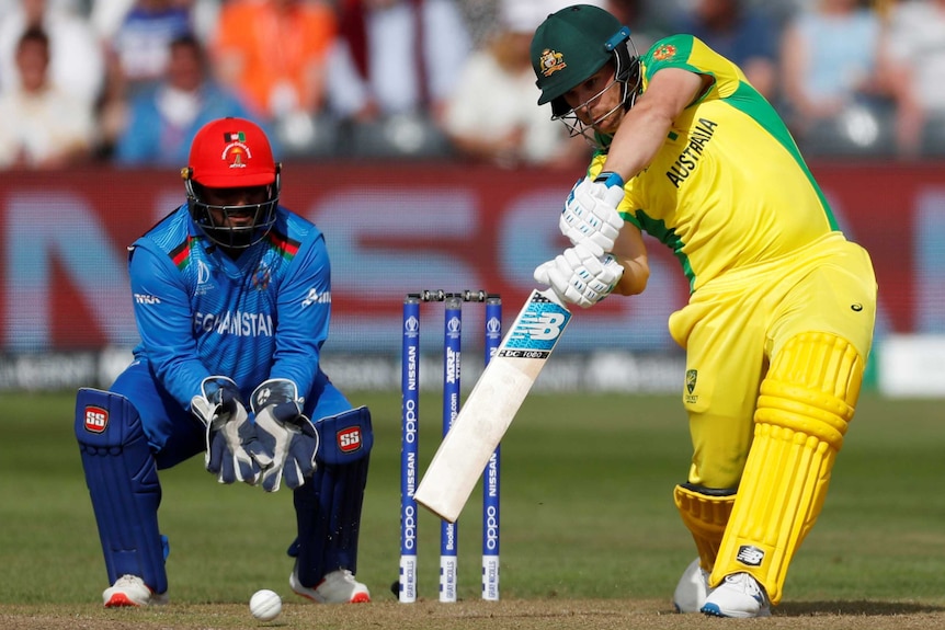 Aaron Finch drives hard through the covers while the wicketkeeper watches on.