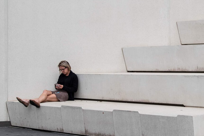 A woman sits smoking on steps