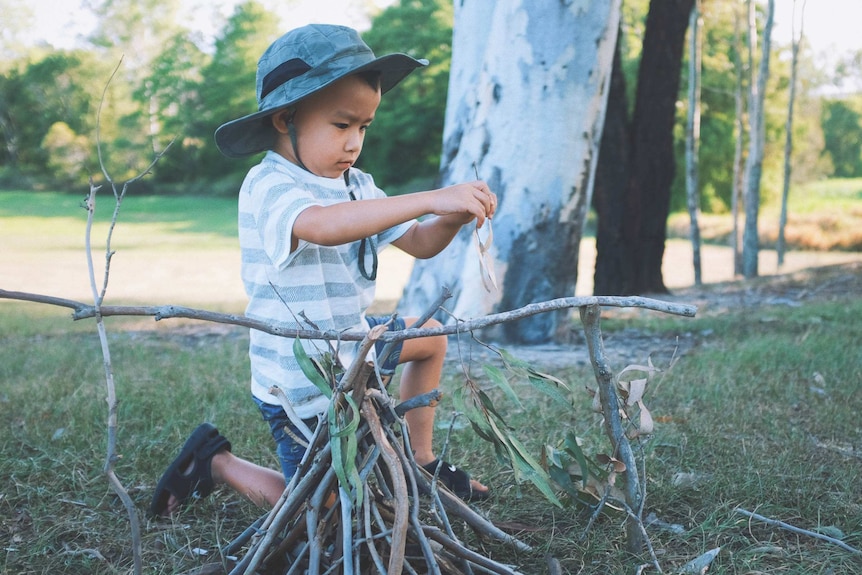 Child wearing hat playing with sticks