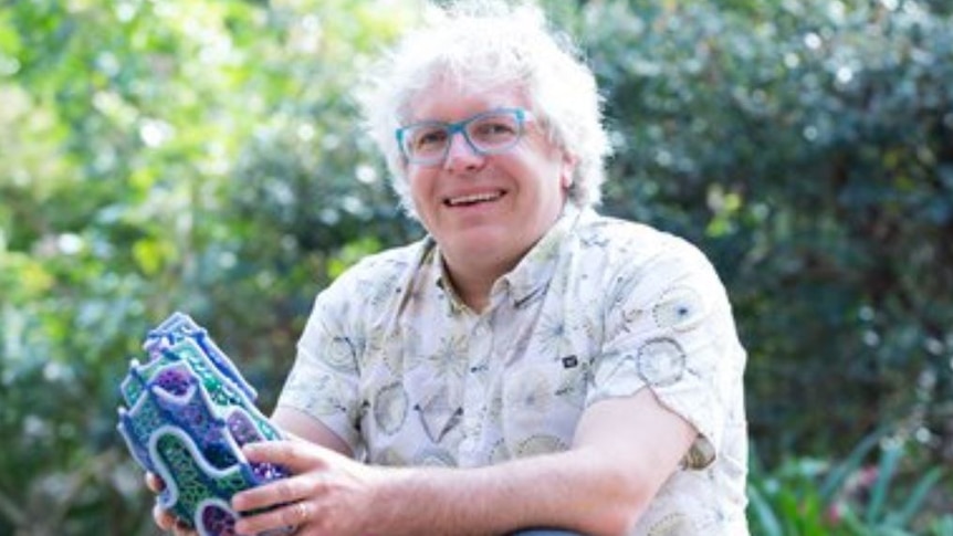 A white haired man smiling at the camera.