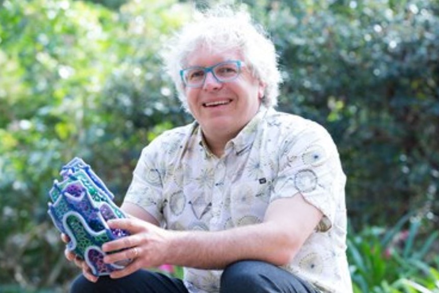 A white haired man smiling at the camera.