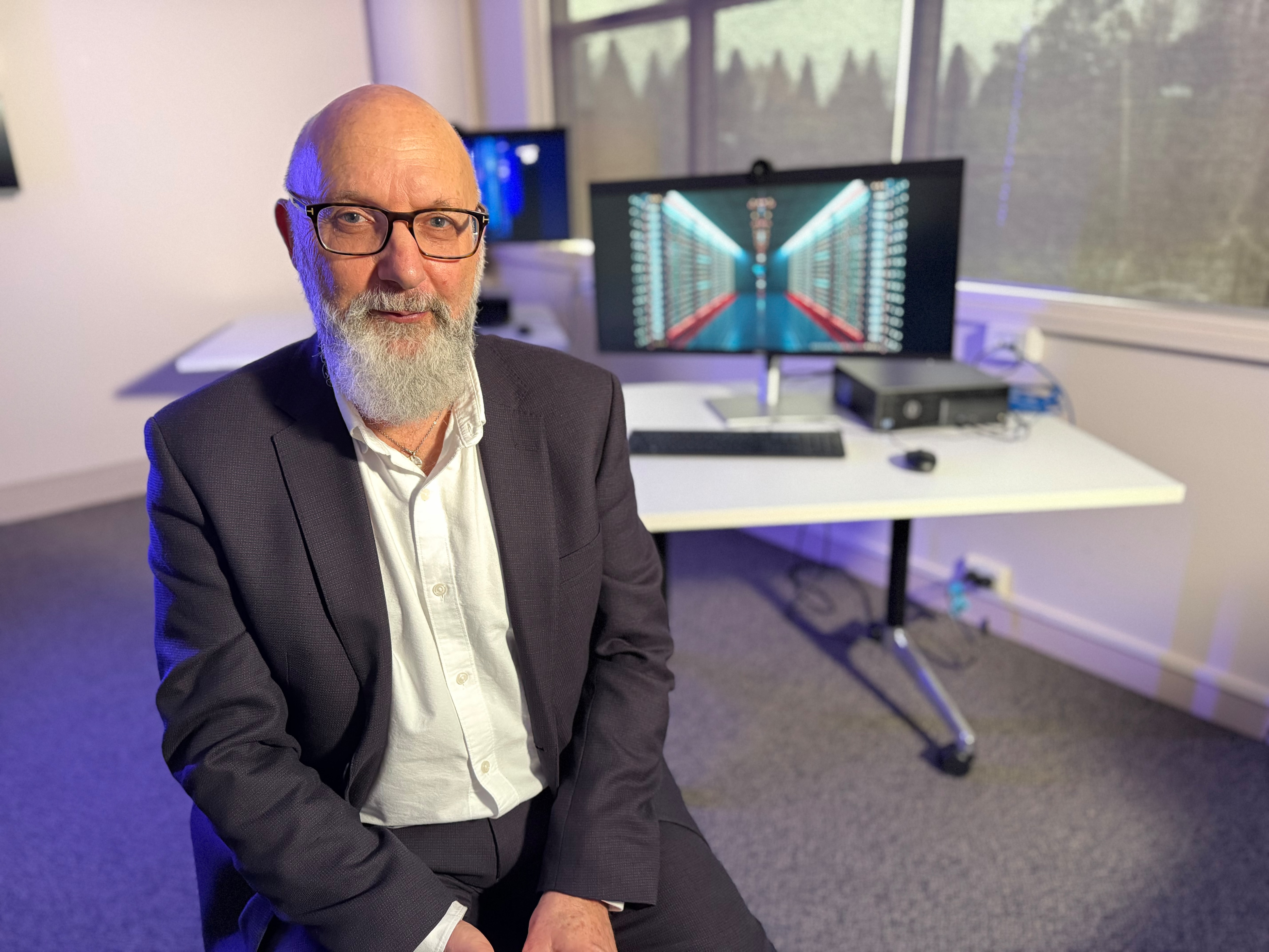 Russell Kelly sitting in front of computers in an office.