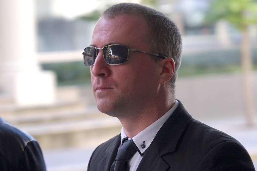 A mid shot of WA Police officer Andrew Barber outside a Perth court with a cameraman behind him.