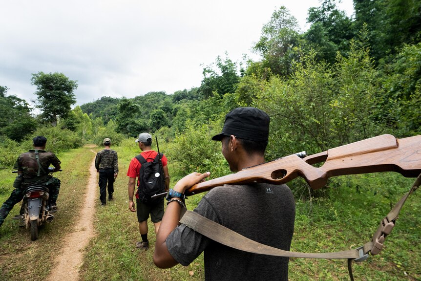 A member of the Karenni People Defense Force holds a rifle as he walks behind other fighters.