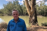 Man stands by on the banks of the Darling River