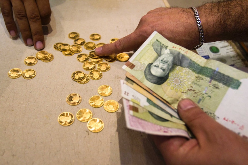 A customer buys Iranian gold coins at a currency exchange office in Tehran's business district.