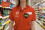 A close up of the torso of a Coles worker in a branded polo shirt, working in a store and wearing a body camera.