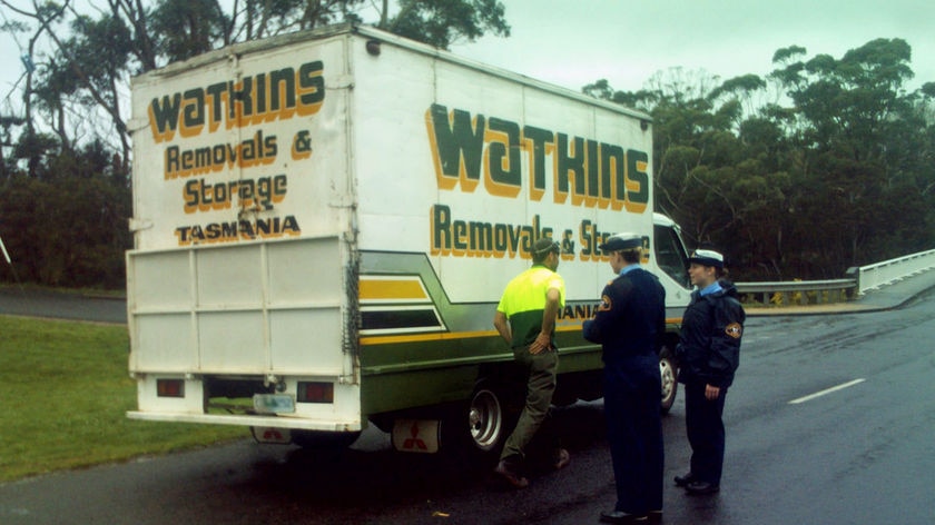 Tasmanian police talk to a truck driver during search for fugitive.