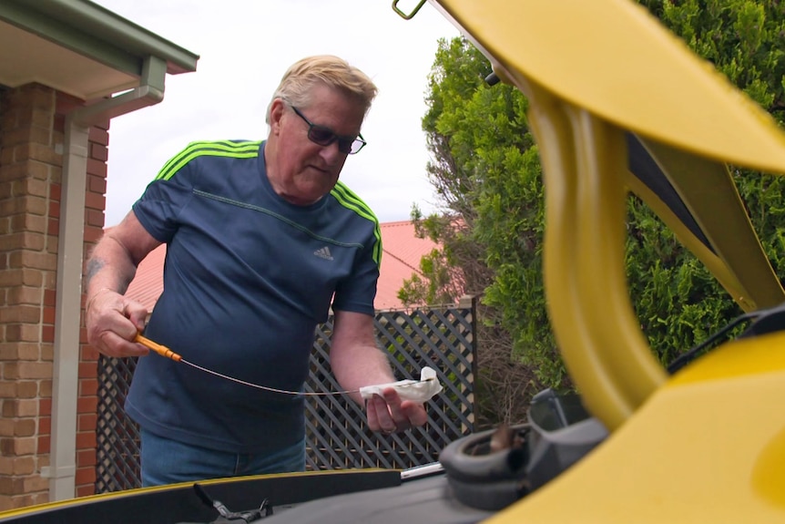 A man checks the oil in his car.