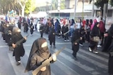 Children wearing a burqa and holding cut-out weapons in parade