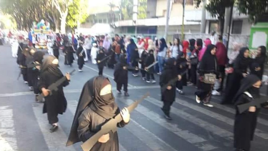 Children wearing a burqa and holding cut-out weapons in parade