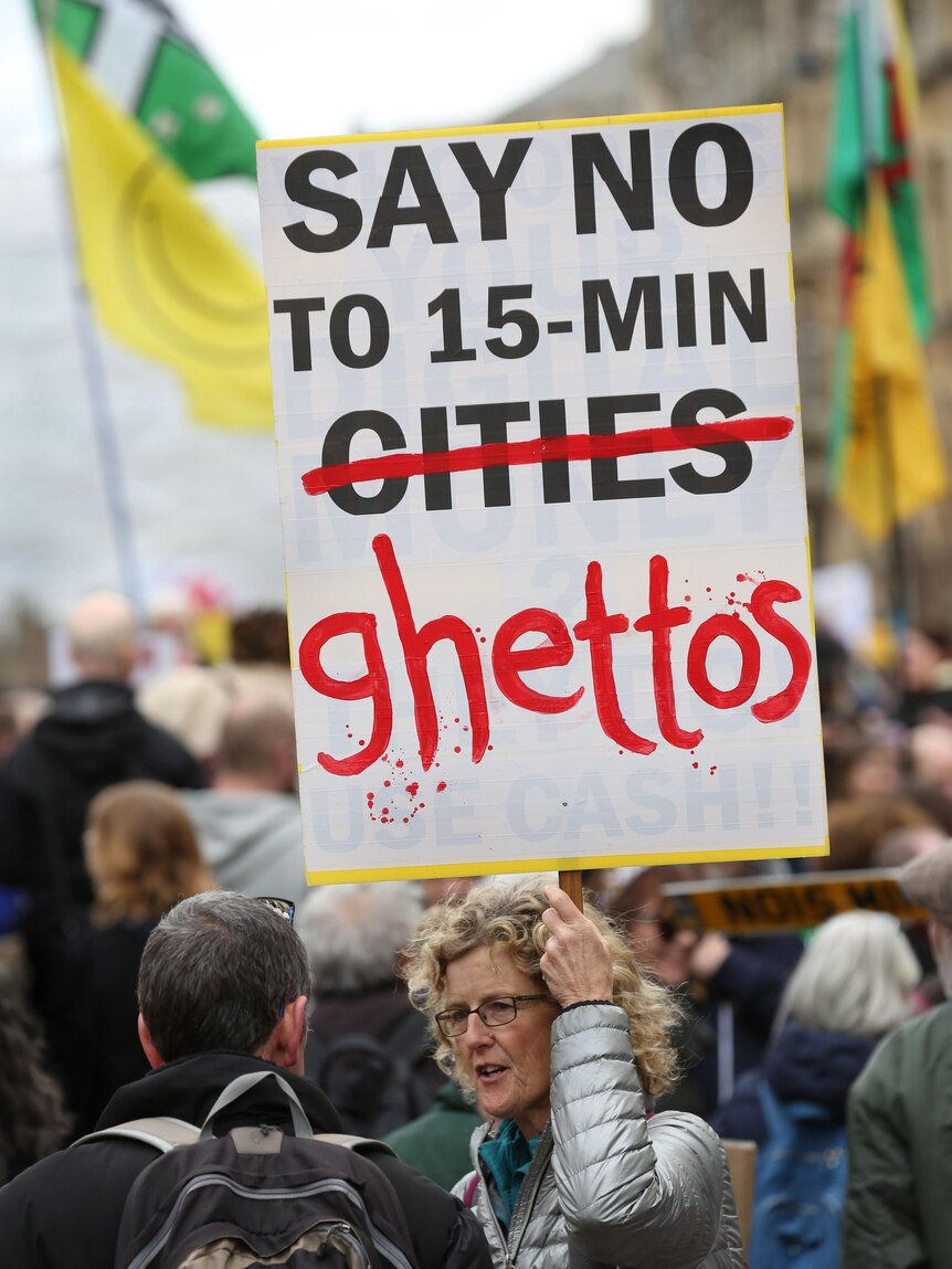 A woman holds a poster that says 'say no to 15-min ghettos' at a protest