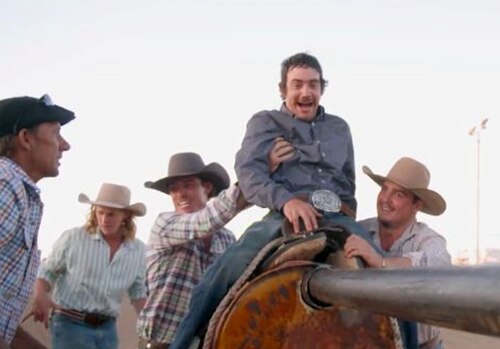 A man being helped onto a saddle by others