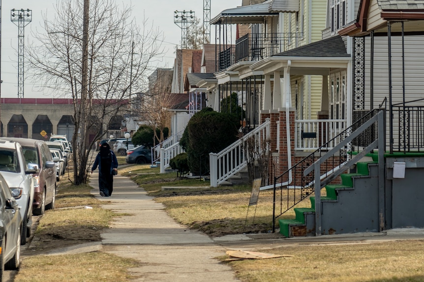A woman wearing a burqa walks up a street in Dearborn