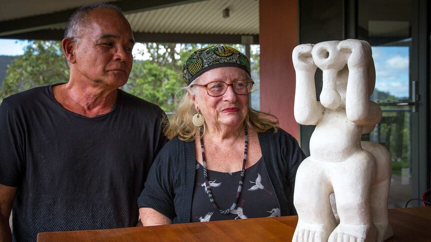 Image of two sculptors sitting at a table admiring a small sculptural work.