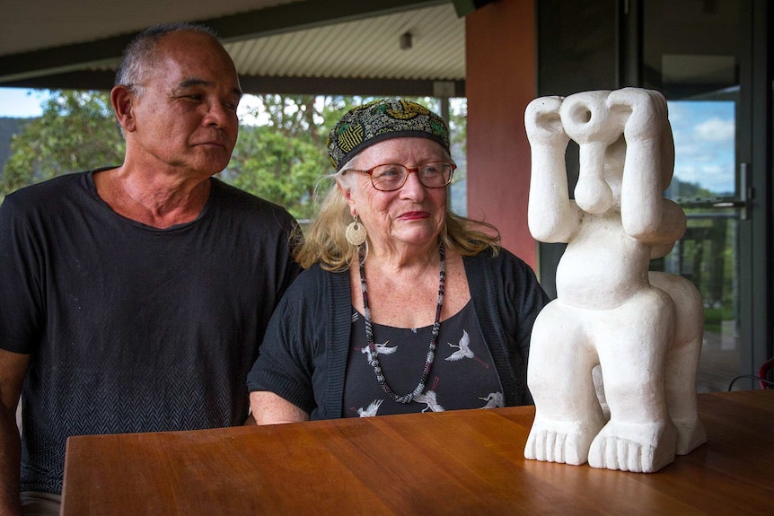 Image of two sculptors sitting at a table admiring a small sculptural work.