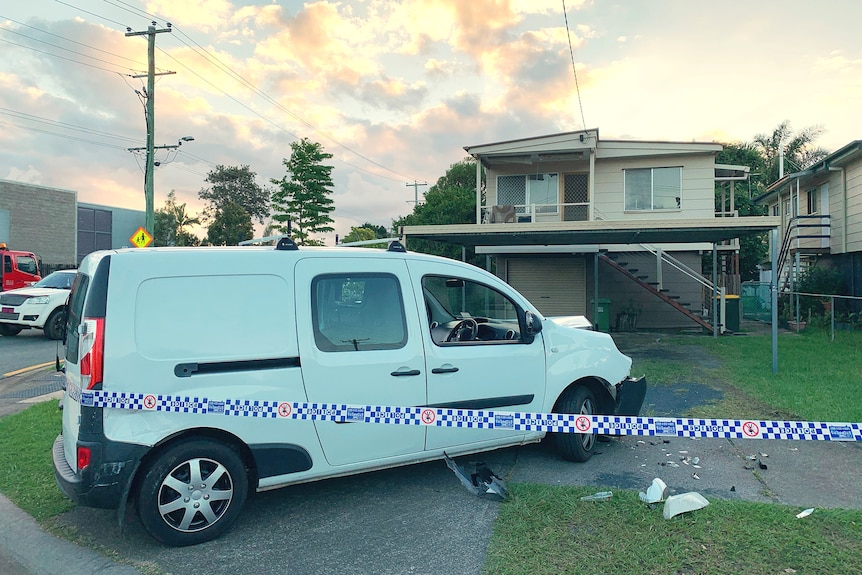 A damaged van on the driveway of a house with police tape across it