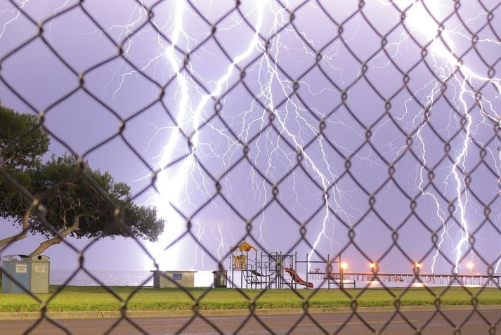 Lightening bolts strike behind a playground and jetty.