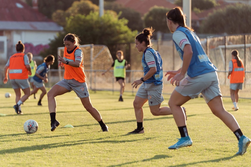 A group of women playing soccer on a sporting field