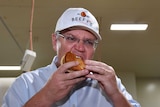 Prime Minister Scott Morrison eats a pie during a visit to the Beefy's Pies factory.
